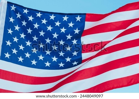 The flag of the United States is flying. The star-spangled flag on the sky background