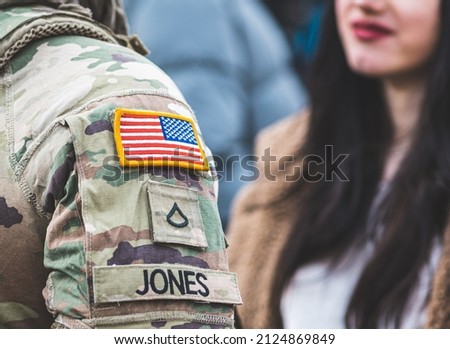 Flag of United States Marine Corps, USA or US army and symbols on an uniform of a soldier talking with a beautiful girl with red lips and black hair, goodbye concept