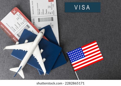 Flag of United States with passport and toy airplane on wooden background. Flight travel concept