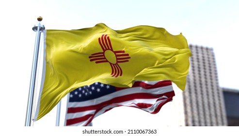 the flag of the US state of New Mexico waving in the wind with the American flag blurred in the background. New Mexico state flag It is one of four U.S. state flags not to contain the color blue