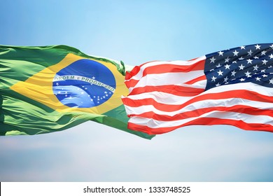 Flag Of The USA And Brazil Against The Background Of The Blue Sky