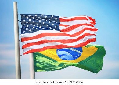 Flag Of The USA And Brazil Against The Background Of The Blue Sky