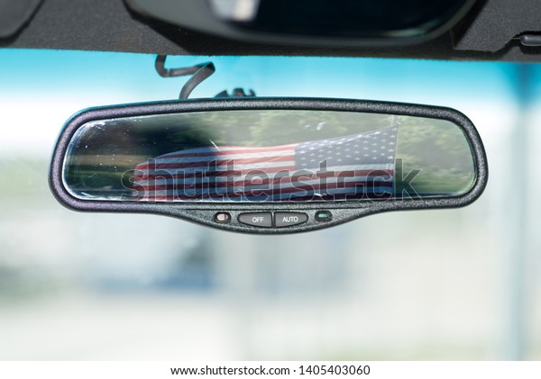 The flag of\
USA in the interior mirror of a\
car