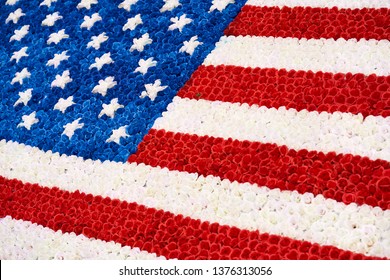 Flag of the USA laid out from red, blue and white flowers outdoors. Closeup. Horizontal.