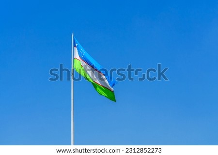 Flag of Uzbekistan waving on a daytime blue sky background.