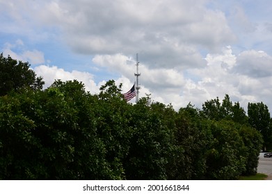 Flag Waves In The Distance Over Trees In A Park In Lexington, SC, USA