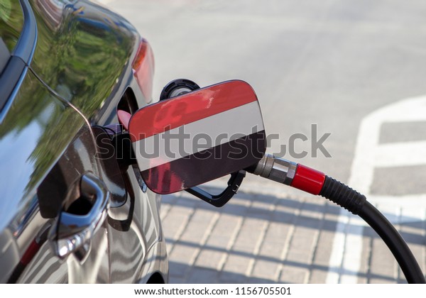 Flag of Yemen on the car\'s fuel tank\
filler flap. Fueling car with petrol pump at a gas station. Petrol\
station. Gasoline and oil products. Close\
up.
