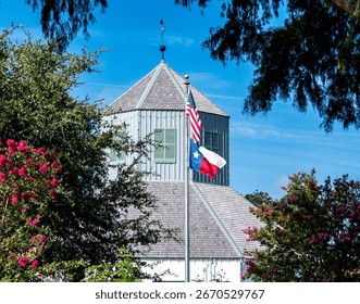 flagpole seen through the trees featuring the American Flag over the Texas Flag