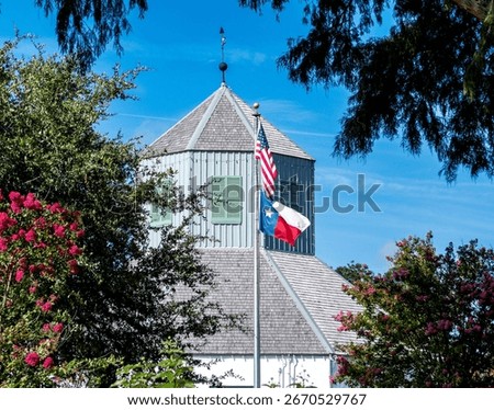 flagpole seen through the trees featuring the American Flag over the Texas Flag