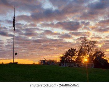 A flagpole with the sunset behind it.