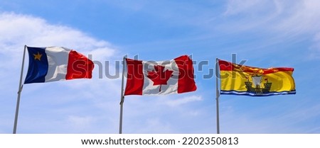 Flags blowing in the wind one of Canada one of New Brunswick and one of Acadia 