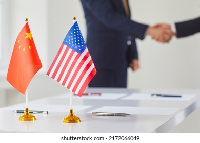 Flags of China and America against background of handshakes of political representatives of these countries. Concept of bilateral political relations and cooperation between United States and China - Powered by Shutterstock