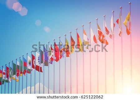 Flags of different countries on the background of the blue sky in the sunlight