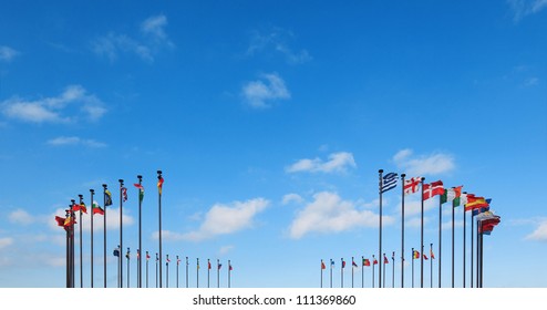 Flags of different countries on a flagpole against a blue sky