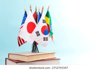 Flags of different countries placed on a table beside books in a classroom setting with a light background