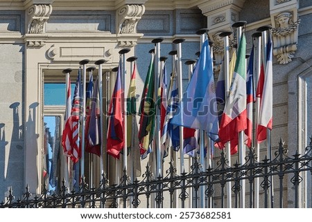 Flags of different countries waving in front of an iconic building in Madrid, symbolizing international cooperation and unity. Perfect for illustrating globalization themes and diplomatic events.
