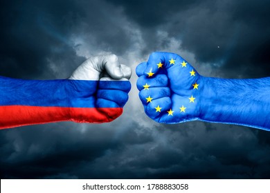 Flags Of EU And Russia Painted On Two Fists On Sky Background. EU Versus  Russia Trade War Disputes Concept.