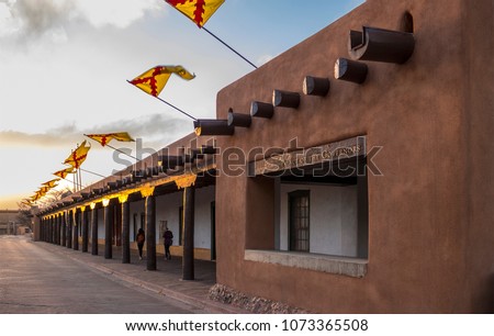 Flags flying above the Palace of the Governors, Santa Fe Plaza, State Capital of New Mexico at sunset on a spring evening. Adobe structure and historical Spanish seat of government in the Southwest. 