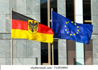 Flags of Germany (Federal Republic of Germany; in German: Bundesrepublik Deutschland) and the European Union (EU) waving in the wind in front of a facade in Berlin on a bright sunny summer day. 