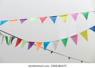 Flags multicolored birthday decoration. Colorful bunting flags hanging on white wall. Wedding decor. Decorative flags of textile for holiday decor hang on rope. Festive bunting flags isolated on white - Powered by Shutterstock