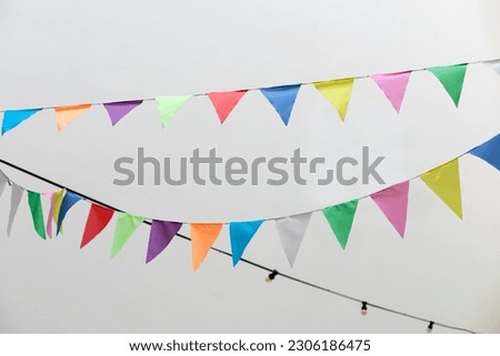 Flags multicolored birthday decoration. Colorful bunting flags hanging on white wall. Wedding decor. Decorative flags of textile for holiday decor hang on rope. Festive bunting flags isolated on white
