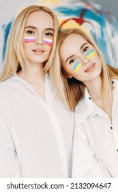 Flags are painted on the girls' faces. Twin sisters with flags of Russia and Ukraine.