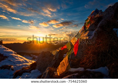 Flags of Tibetan prayers in the mountains with the colors of a warm sunset.
