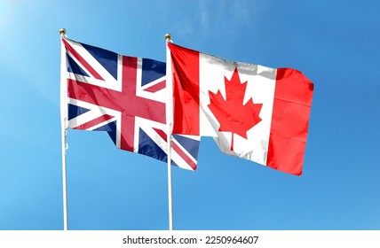Flags of Union Jack and Canadian flag against cloudy sky. waving in the sky - Shutterstock ID 2250964607