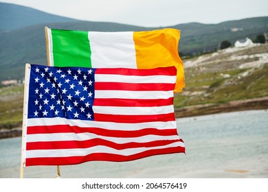 Flags Of United States Of America And National Flag Of Ireland. Green Rural Area With Mountains And Ocean In The Background. County Mayo, Ireland. Bond Between Two Great Countries Concept.