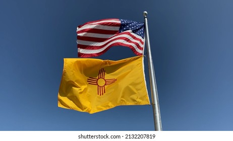 Flags of United States of America and the State of New Mexico waving in the wind against a blue sky