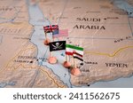 Flags of the United States and Iran and their respective allies surrounding a pirate insignia onto a map of the Red Sea region. It symbolically represents the intricate geopolitical dynamics and