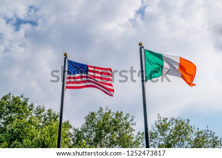 Flags of United states and Ireland fluttering against a blue sky, near Rhode Island irish famine memorial, Providence, USA