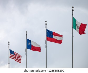 Flags Of The Untied States Of America, The State Of Texas, The First Official National Flag Of The Confederacy And Of Mexico Waving In The Wind Against A Cloudy Sky