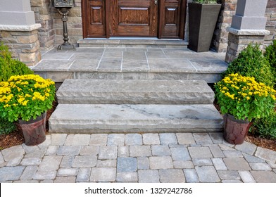Flagstone applied to the original concrete veranda, natural stone steps, and paver walkway all provide a beautiful, fresh landscape update to this stately home.