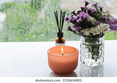Flame burning at aroma candle puts near by window with rain drop in monsoon season. Zen and relax concept. - Shutterstock ID 2318634003