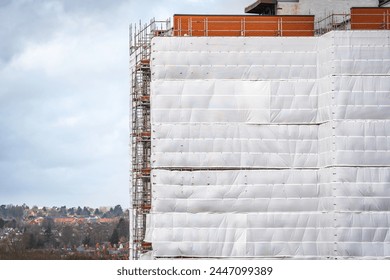 Flame retardant scaffold sheeting wrapped apartments building during insulation in england uk.