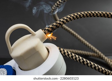 flame smoke and sparks on an electrical cable with fabric insulation, fire hazard concept, soft focus close up