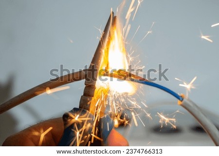 flame and sparks with pliers cutting  electrical cables, fire hazard concept, soft focus close up