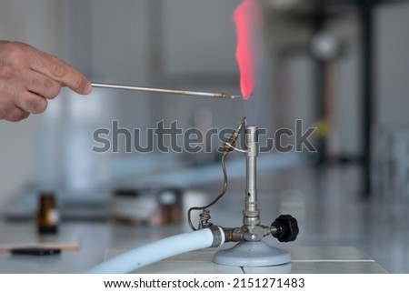 Flame test burning into chemistry laboratory. Lithium reaction over bunsen