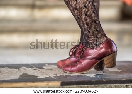 Flamenco dancers legs in red shoes close-up, Andalusia, Spain. Traditional Spanish flamenco dance shoes, leather high heels. Woman dancing flamenco in black stockings and leather shoes.