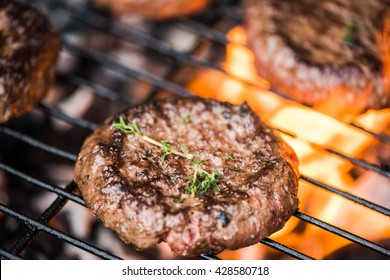 Flames From Bbq Grill And Beef Burgers With Fresh Herbs