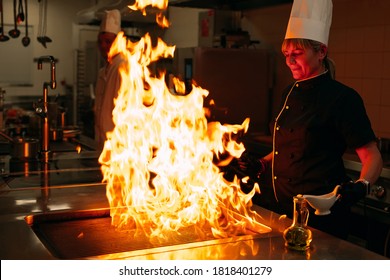 The Flames In The Kitchen Of The Restaurant. The Chef Prepares A Steak In The Restaurant's Kitchen