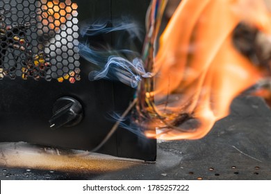 Flaming Electric Wires In Broken Wrecks On Air, Road Or Rail Crash. Burned Cables In Fire And Smoke. Black Metal Cover Detail With Round Control Knob And Hexagonal Grid. Abstract Industrial Accident.