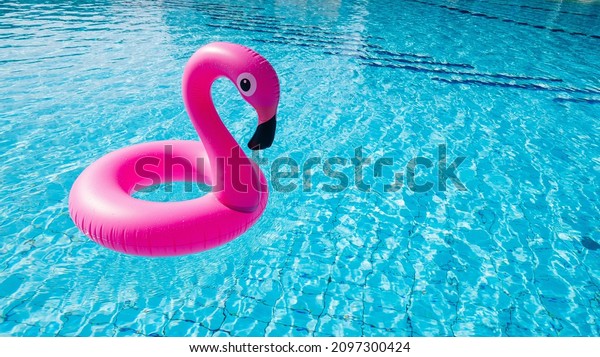 Flamingo plastic. Pink\
inflatable flamingo in pool water for beach background. Trendy\
summer concept