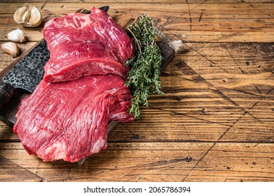 Flank raw beef steaks on a butcher cutting board with knife. wooden background. Top view. Copy space.