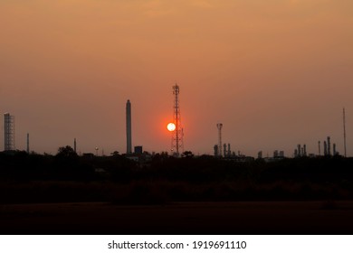 Flare stack or Ventilation industrial and Communication Telephone towers in theIndustrial estate, factory petrochemical plant at evening sunset on golden sky with PM2.5 dust background