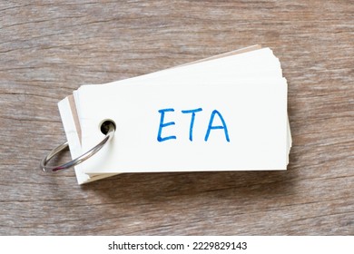 Flash card with handwriting in word ETA (abbreviation of estimated time of arrival) on wood background - Shutterstock ID 2229829143
