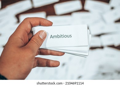 Flash Card with the Word Ambitious  Held Against Background of scattered Flash Cards