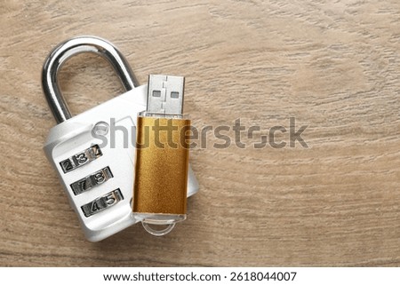 Flash drive and combination padlock on wooden background, top view. Space for text