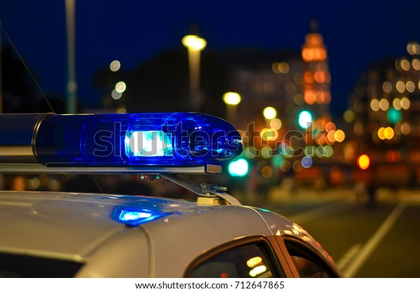 A flasher on the roof of a police car. Police.\
Background - city lights.